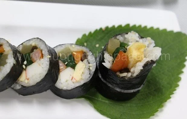 Cắt cơm cuộn thành những khoanh tròn nhỏ vừa ăn bày lên đĩa Cắt cơm cuộn thành những khoanh tròn nhỏ vừa ăn bày lên đĩa